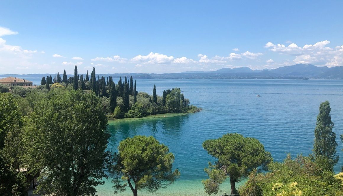 L'immagine mostra una giornata al lago di Garda immerso nella natura, un luogo perfetto per i viaggiatori che vogliono fare una gita a bordo di camper, va, caravan e roulotte